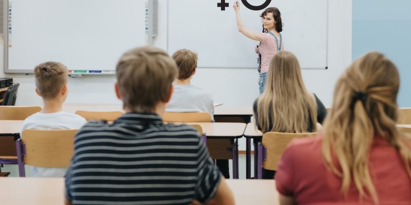 Young teacher is standing in front of the blackboard during sex education lesson